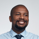 Image of a smiling office professional wearing a blue button down shirt and tie